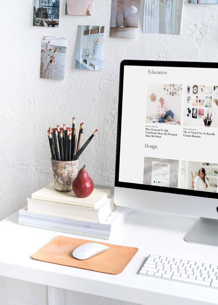 iMac on a desk with books next to it and photographs on the wall behind it preparing for an on-brand photoshoot